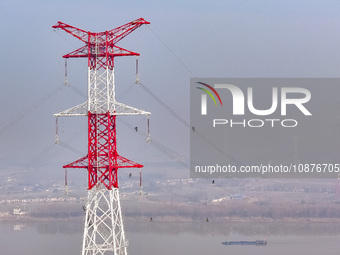 Construction workers are performing an acceptance check on the 200 kV DC transmission line project, which is 100 meters high, in Yangzhou, J...