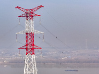 Construction workers are performing an acceptance check on the 200 kV DC transmission line project, which is 100 meters high, in Yangzhou, J...