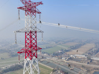 Construction workers are performing an acceptance check on the 200 kV DC transmission line project, which is 100 meters high, in Yangzhou, J...