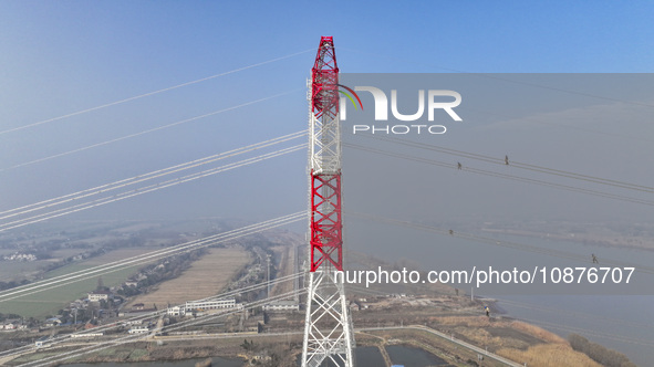 Construction workers are performing an acceptance check on the 200 kV DC transmission line project, which is 100 meters high, in Yangzhou, J...