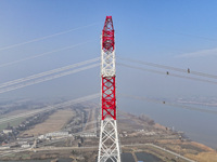 Construction workers are performing an acceptance check on the 200 kV DC transmission line project, which is 100 meters high, in Yangzhou, J...