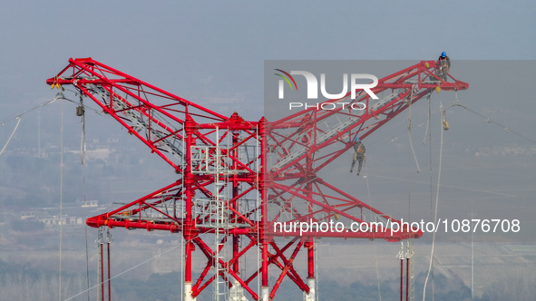 Construction workers are performing an acceptance check on the 200 kV DC transmission line project, which is 100 meters high, in Yangzhou, J...