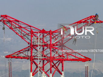 Construction workers are performing an acceptance check on the 200 kV DC transmission line project, which is 100 meters high, in Yangzhou, J...