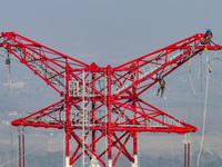 Construction workers are performing an acceptance check on the 200 kV DC transmission line project, which is 100 meters high, in Yangzhou, J...