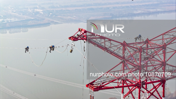 Construction workers are performing an acceptance check on the 200 kV DC transmission line project, which is 100 meters high, in Yangzhou, J...