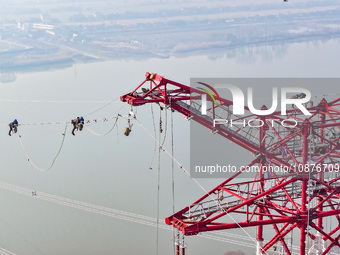 Construction workers are performing an acceptance check on the 200 kV DC transmission line project, which is 100 meters high, in Yangzhou, J...