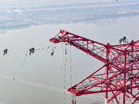 Construction workers are performing an acceptance check on the 200 kV DC transmission line project, which is 100 meters high, in Yangzhou, J...