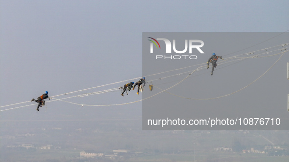 Construction workers are performing an acceptance check on the 200 kV DC transmission line project, which is 100 meters high, in Yangzhou, J...