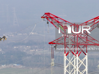 Construction workers are performing an acceptance check on the 200 kV DC transmission line project, which is 100 meters high, in Yangzhou, J...