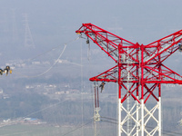 Construction workers are performing an acceptance check on the 200 kV DC transmission line project, which is 100 meters high, in Yangzhou, J...