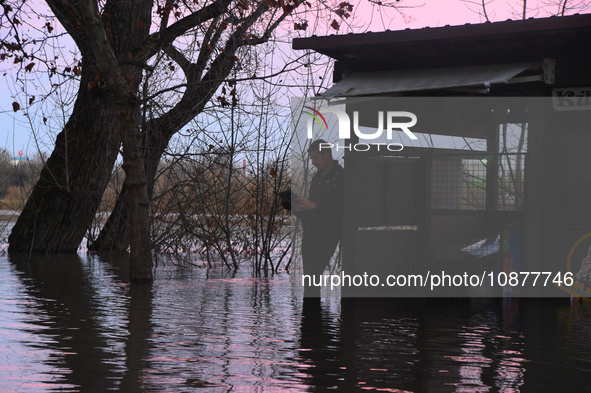 A man is reading a paper near a submerged restaurant on the bank of the Danube as a wave of floods is expected on the river, in Budapest, Hu...