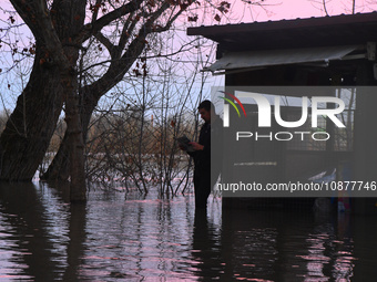 A man is reading a paper near a submerged restaurant on the bank of the Danube as a wave of floods is expected on the river, in Budapest, Hu...