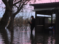 A man is reading a paper near a submerged restaurant on the bank of the Danube as a wave of floods is expected on the river, in Budapest, Hu...