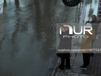 Passersby are looking at the flooding Danube as a wave of floods is expected on the river, in Budapest, Hungary, on December 28, 2023.  (