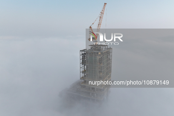 Workers are working on the 416.6-meter-high Hexi City II roof in heavy fog in Nanjing, Jiangsu Province, China, on December 29, 2023. 