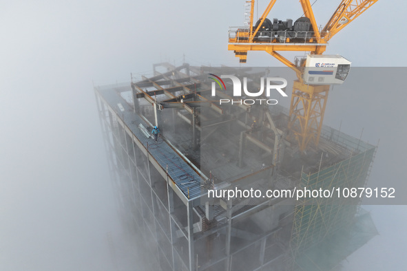 Workers are working on the 416.6-meter-high Hexi City II roof in heavy fog in Nanjing, Jiangsu Province, China, on December 29, 2023. 