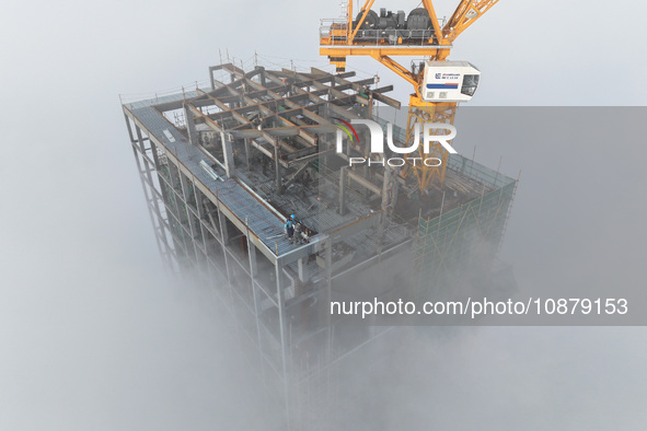 Workers are working on the 416.6-meter-high Hexi City II roof in heavy fog in Nanjing, Jiangsu Province, China, on December 29, 2023. 