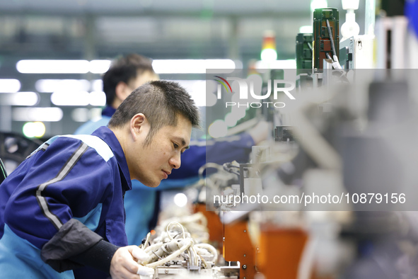 A worker is working on the production line of an electronic components company in Suqian, Jiangsu Province, China, on December 29, 2023. 