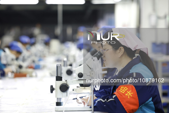 Workers are working on the production line of an electronic components company in Suqian, Jiangsu province, China, on December 29, 2023. 