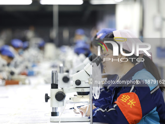 Workers are working on the production line of an electronic components company in Suqian, Jiangsu province, China, on December 29, 2023. (