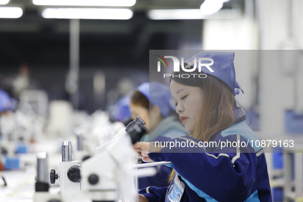 Workers are working on the production line of an electronic components company in Suqian, Jiangsu province, China, on December 29, 2023. 