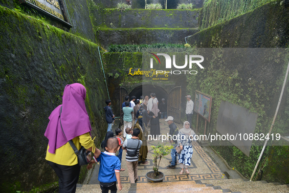 People are standing near the entrance of Lobang Jepang (Japanese tunnel), a historical tourist attraction in Bukittinggi, West Sumatra, Indo...