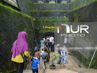 People are standing near the entrance of Lobang Jepang (Japanese tunnel), a historical tourist attraction in Bukittinggi, West Sumatra, Indo...