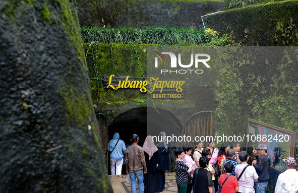 People are standing near the entrance of Lobang Jepang (Japanese tunnel), a historical tourist attraction in Bukittinggi, West Sumatra, Indo...