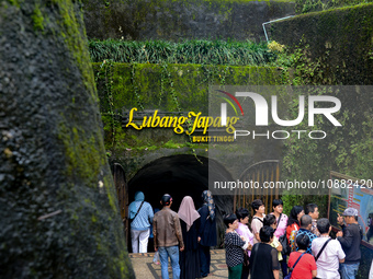 People are standing near the entrance of Lobang Jepang (Japanese tunnel), a historical tourist attraction in Bukittinggi, West Sumatra, Indo...