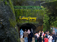 People are standing near the entrance of Lobang Jepang (Japanese tunnel), a historical tourist attraction in Bukittinggi, West Sumatra, Indo...