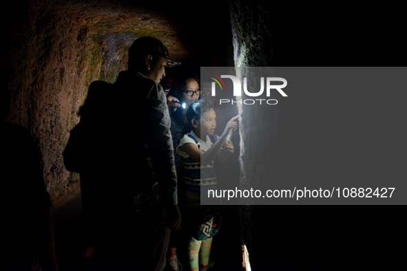 A guide is accompanying tourists as they visit the Japanese tunnel, also known as Lobang Jepang, at the historical tourist attraction in Buk...