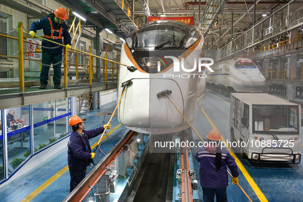 Workers are cleaning the front of a bullet train at the maintenance depot of the Nanjing South Railway Station in Nanjing, China, on January...