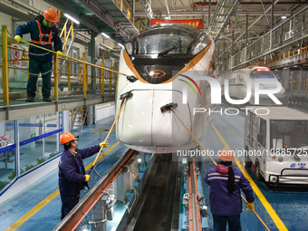 Workers are cleaning the front of a bullet train at the maintenance depot of the Nanjing South Railway Station in Nanjing, China, on January...