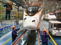 Workers are cleaning the front of a bullet train at the maintenance depot of the Nanjing South Railway Station in Nanjing, China, on January...