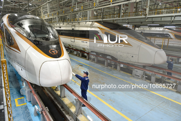 Workers are inspecting an EMU train at the inspection depot of the Nanjing South Bullet Train station in Nanjing, Jiangsu Province, China, o...