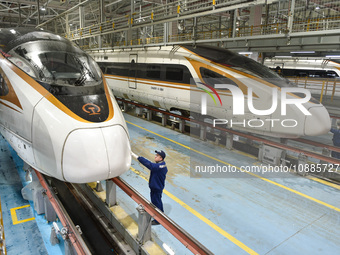 Workers are inspecting an EMU train at the inspection depot of the Nanjing South Bullet Train station in Nanjing, Jiangsu Province, China, o...