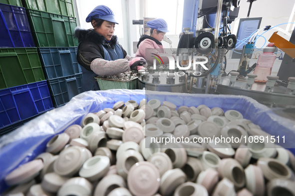 Workers are working in a production workshop of a bottle cap company in Tashan town, Ganyu district, Lianyungang city, Jiangsu province, Eas...