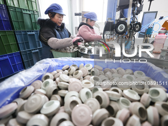 Workers are working in a production workshop of a bottle cap company in Tashan town, Ganyu district, Lianyungang city, Jiangsu province, Eas...