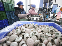 Workers are working in a production workshop of a bottle cap company in Tashan town, Ganyu district, Lianyungang city, Jiangsu province, Eas...