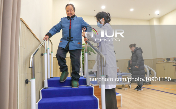 An elderly man is being escorted by medical staff during rehabilitation training in the rehabilitation sports function room of the Wuyang St...