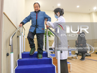 An elderly man is being escorted by medical staff during rehabilitation training in the rehabilitation sports function room of the Wuyang St...