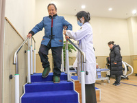 An elderly man is being escorted by medical staff during rehabilitation training in the rehabilitation sports function room of the Wuyang St...