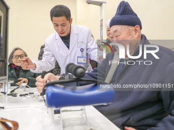 An elderly man is being escorted by medical staff during rehabilitation training in the rehabilitation sports function room of the Wuyang St...