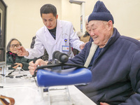 An elderly man is being escorted by medical staff during rehabilitation training in the rehabilitation sports function room of the Wuyang St...