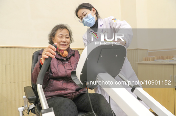 An elderly man is being escorted by medical staff during rehabilitation training in the rehabilitation sports function room of the Wuyang St...