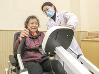 An elderly man is being escorted by medical staff during rehabilitation training in the rehabilitation sports function room of the Wuyang St...