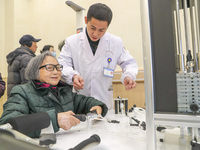 An elderly man is being escorted by medical staff during rehabilitation training in the rehabilitation sports function room of the Wuyang St...