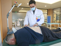 A medical worker is performing traditional Chinese medicine therapy for an elderly person at a community health service center on Wuyang Str...