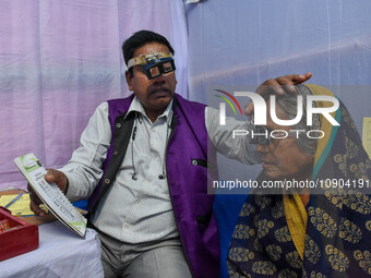 A doctor is checking the eyesight of a traveling devotee at a free checkup camp in Gangasagar transit camp in Kolkata, India, on January 11,...