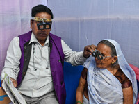 A doctor is checking the eyesight of a traveling devotee at a free checkup camp in Gangasagar transit camp in Kolkata, India, on January 11,...